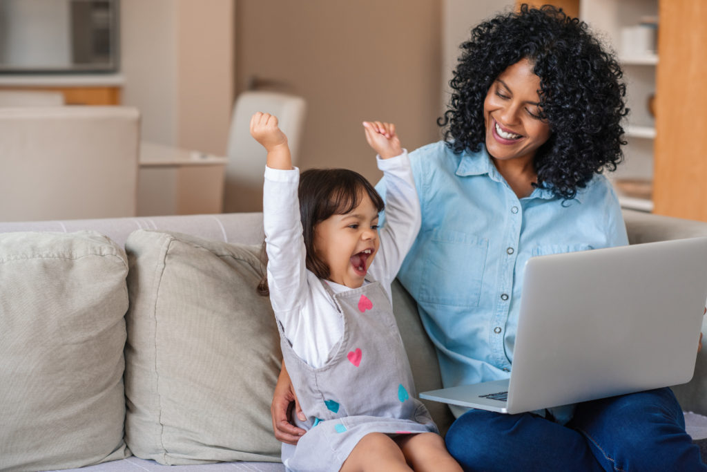 Excited little girl with mother while using a laptop