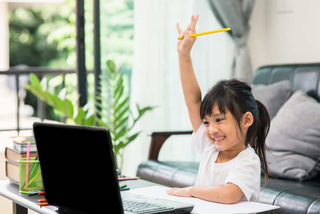 Young girl raising her hand during online instruction