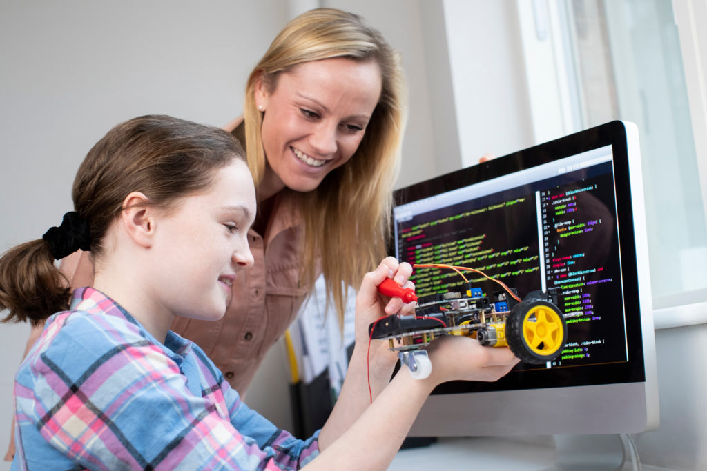 Teacher and student with robot and programming code on a computer