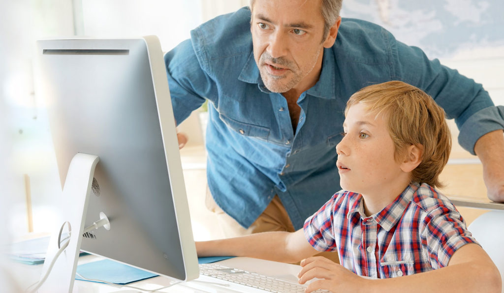 A man helping a boy at a computer