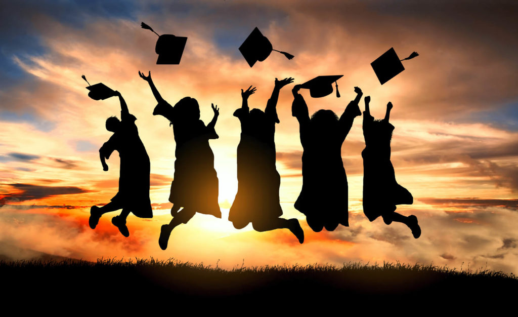 Graduates jumping in front of a sunset