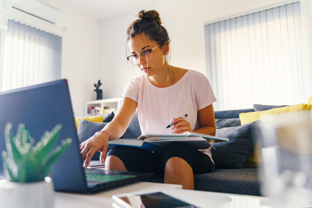 Student working on a laptop in a sunlit room