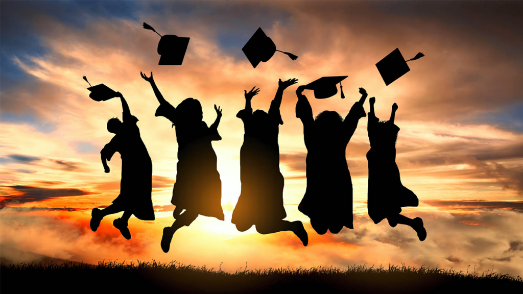 A group of graduates jumping while throwing their caps