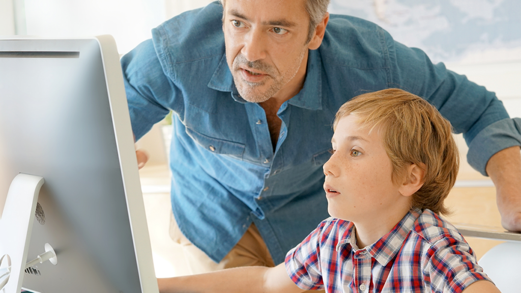 A man helping a boy at a computer