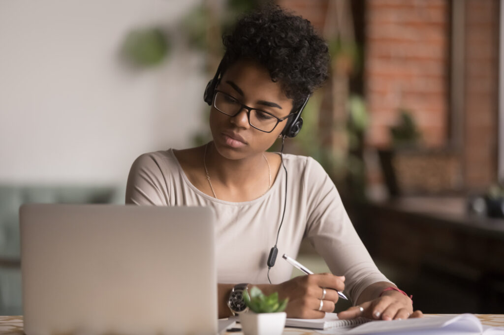 Student using a laptop and writing notes